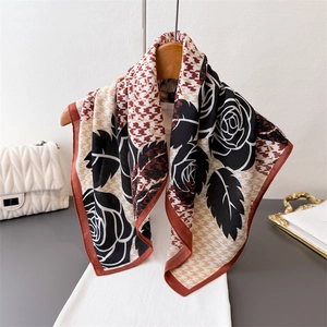 Vintage sjaal met rozen en houndstooth-patroon hangend aan een houten kledinghanger