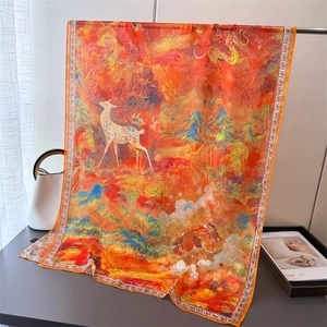 Detail of silk scarf with artistic deer and landscape illustration in vibrant orange
