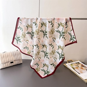 Close-up of floral pattern silk scarf with daisy prints and burgundy hem finish