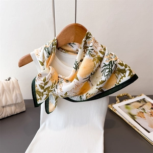 Detail of floral daisy print silk scarf tied on a white top with elegant accessories