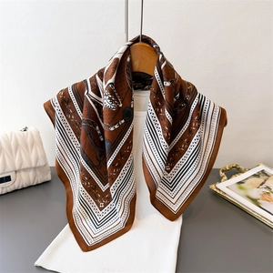 Elegant chain pattern square scarf in silk-like fabric hanging on a wooden hanger
