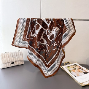 Detail of horse chain pattern silk scarf hanging elegantly with a quilted bag