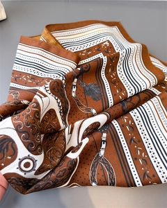 Detail of silk-like scarf featuring equestrian chain motifs and retro badge patterns