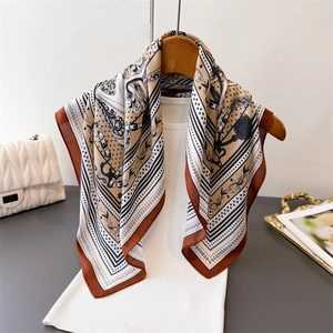 Caramel and beige chain pattern silk-like square scarf draped on a white shirt