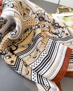 Macro view showing the intricate chain and floral twill texture of this luxury silk scarf
