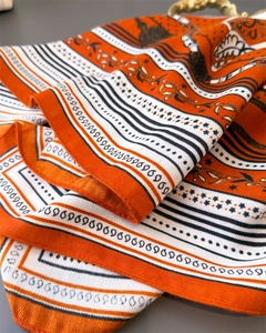Detail of orange chain pattern silk scarf with golden metal ring and twill texture