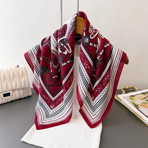 Elegant burgundy chain pattern silk-like scarf draped on a wooden hanger with fashion props