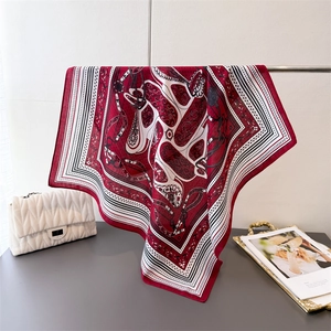 Detailed view of large square silk scarf with classic red and white equestrian pattern