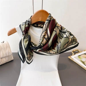 Leaf print silk scarf with herringbone texture displayed on a wooden hanger with white top