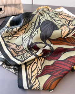 Detail view of tropical leaf pattern silk scarf on elegant quilted white bag