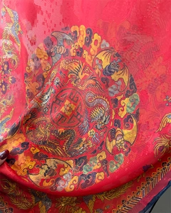 Macro detail of red silk scarf with traditional Chinese dragon and phoenix patterns