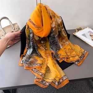 Elegant gradient floral print long silk scarf displayed on a stand with a stylish handbag