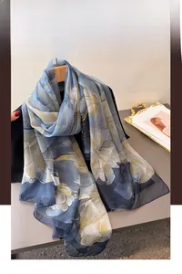 Detail of floral print silk scarf in grey-blue with large yellow flowers on wooden hanger