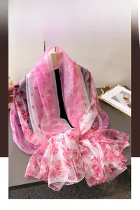 Detail shot of lightweight floral print silk scarf featuring pink petals and soft texture