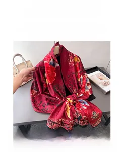 Detail of red silk scarf with peony floral print draped by a yellow handbag and magazine