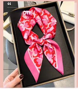Detailed view of pink and red heart-print silk scarf tied inside a display tray