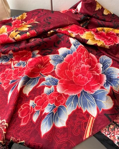 Close-up of red silk scarf showing floral peony patterns and golden cloud texture