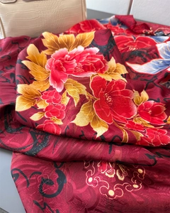 Macro detail of red peony silk scarf showing floral print and soft drape texture