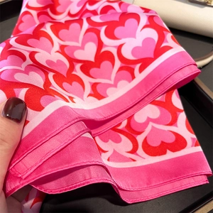 Detail of pink silk scarf with layered heart patterns and smooth satin texture