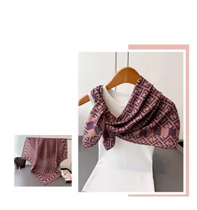 Detail view of the luxury silk scarf showing brown herringbone pattern and F monogram