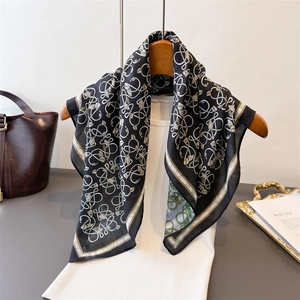 Double-sided herringbone silk scarf with abstract patterns on a wooden hanger