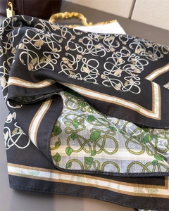 Close-up of double-sided herringbone silk scarf with green leaves and gold vine patterns