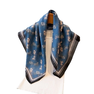 Blue silk scarf with horse carriage pattern hanging on a white mannequin torso