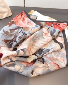 Detailed close-up of the elegant floral print and high-quality hemmed edges on the silk scarf