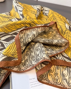 Detailed close-up of double-sided silk scarf with yellow feathers and herringbone pattern
