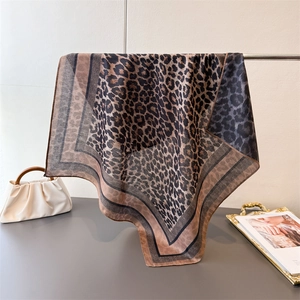 Classic leopard print silk square scarf with geometric border on a display stand