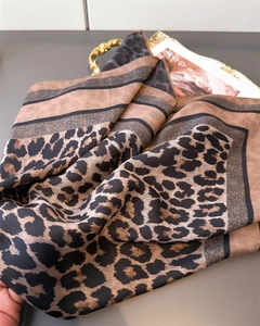 Detail of leopard print shawl with brown tones and striped edges on a stylist backdrop