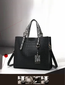 Detail of black crocodile pattern tote bag with grey snakeskin texture handles and strap