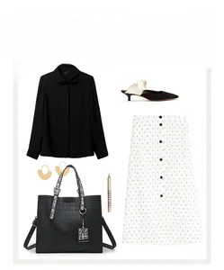 Flat lay of black crocodile pattern handbag with matching polkadot skirt and accessories