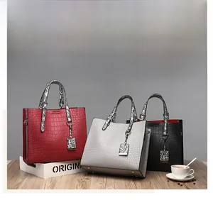Detailed view of crocodile pattern tote bags in burgundy, light grey, and black colors