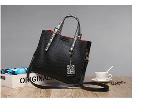 Detail of black crocodile texture tote with snakeskin handles and red lining