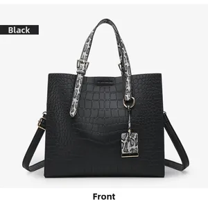 Detail of black crocodile-embossed tote bag featuring a snakeskin pattern handle