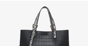 Close-up of black crocodile pattern handbag with snakeskin handles and red lining detail