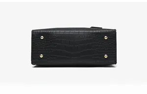 Detail view of the black croc-embossed bucket bag bottom with four gold metal feet studs