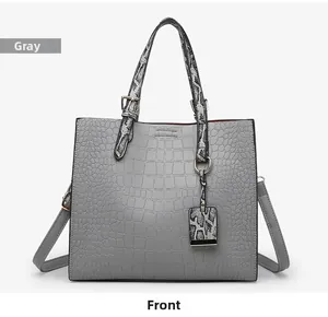 Detail of grey crocodile embossed tote bag with snakeskin print handles and gold hardware