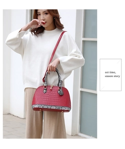 Détail du sac rouge à motif croco avec des accents de poignée élégants en peau de serpent