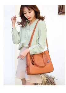 Close-up of orange-brown leather handbag with litchi texture and adjustable strap
