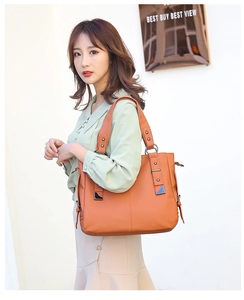 Detail of dark orange pebble grain leather tote bag with wide handles and side hardware