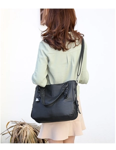 Rear view of black lychee grain leather tote bag with adjustable straps on model