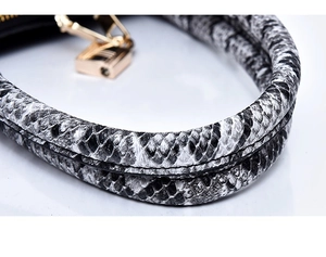 Détail de la poignée en serpent du sac avec fermoir doré métallique et couture précise