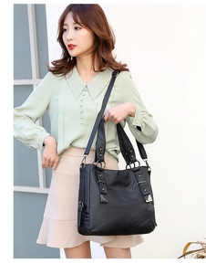 Detail of black pebbled leather tote bag featuring silver rivets and metal ring accents