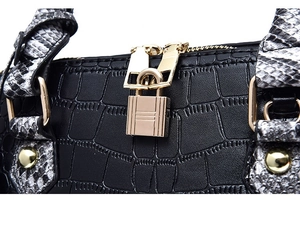 Détail d'un sac à main noir motif crocodile avec fermoir doré et bandoulière serpent