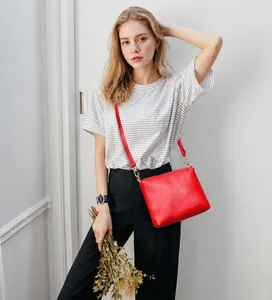Detail of red crossbody bag with lychee pattern texture and golden hardware accents