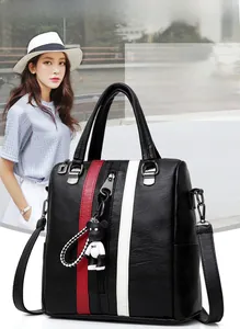 Detail of black pebbled leather backpack with red-white stripes and cute bear charm