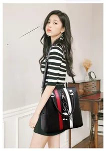 Close-up of black leather handbag featuring red and white stripes and a cute bear charm