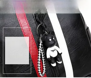 Detail of black lychee grain leather backpack with contrast stripes and bear charm